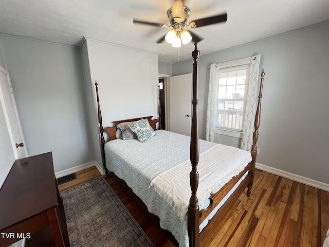 bedroom with ceiling fan, wood finished floors, visible vents, and baseboards