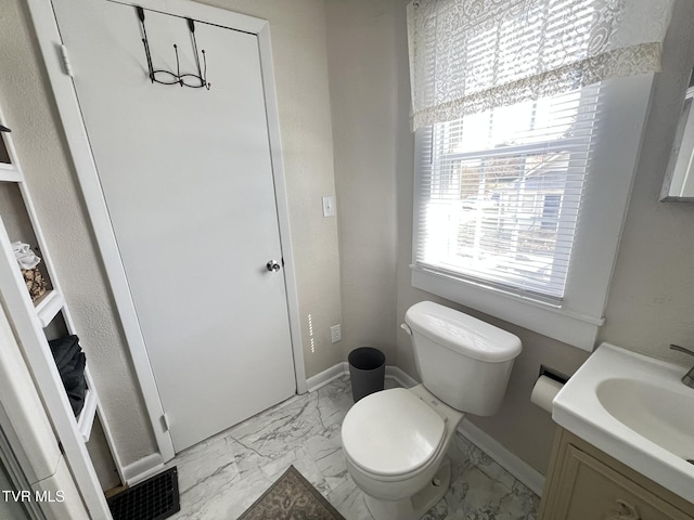 bathroom featuring marble finish floor, baseboards, vanity, and toilet