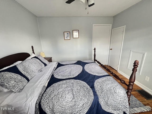 bedroom featuring baseboards, ceiling fan, visible vents, and wood finished floors