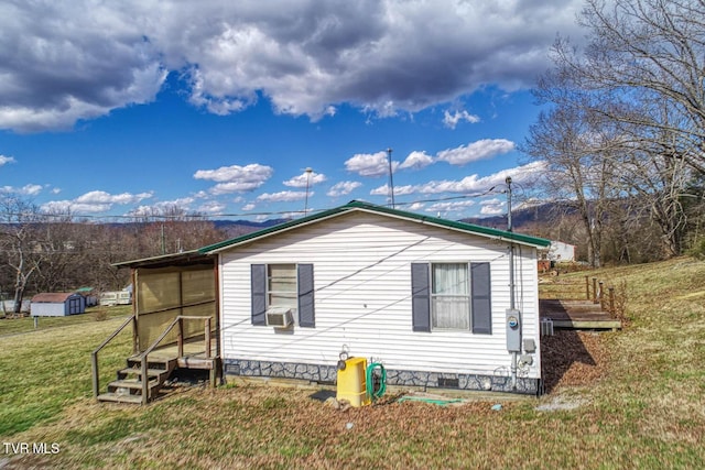 view of side of property with crawl space and a yard