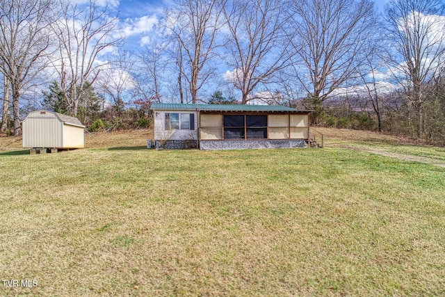 view of front facade featuring metal roof, a shed, an outbuilding, and a front yard