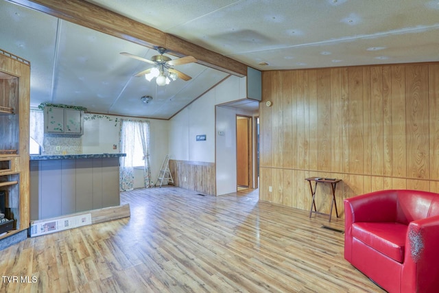 interior space with visible vents, lofted ceiling with beams, a ceiling fan, wood walls, and wood finished floors