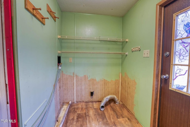 clothes washing area featuring laundry area, a textured ceiling, electric dryer hookup, and wood finished floors