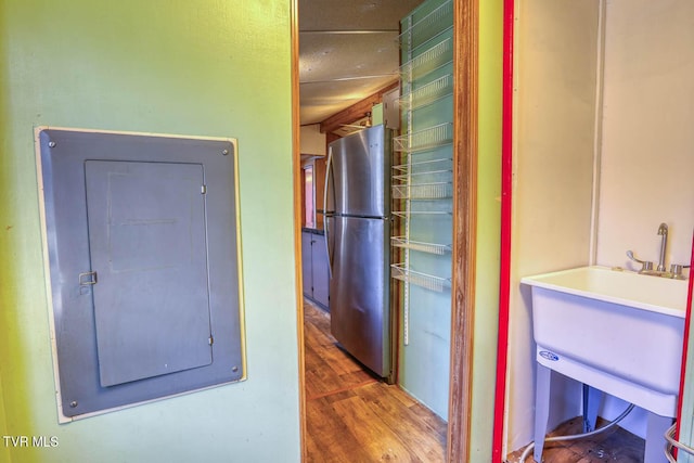 interior space featuring a sink, electric panel, wood finished floors, and freestanding refrigerator