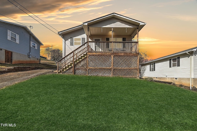 back of property at dusk with stairs, a deck, and a lawn