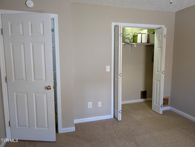 unfurnished bedroom with a spacious closet, a closet, carpet, and baseboards