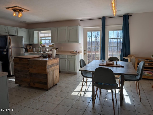 kitchen featuring a kitchen island, light tile patterned flooring, light countertops, and freestanding refrigerator