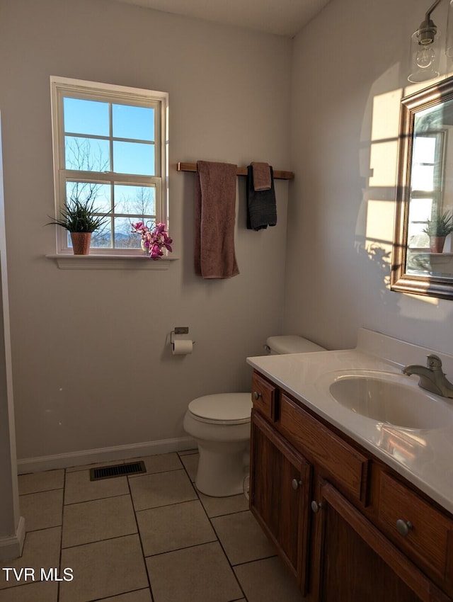 half bath with visible vents, toilet, vanity, tile patterned flooring, and baseboards