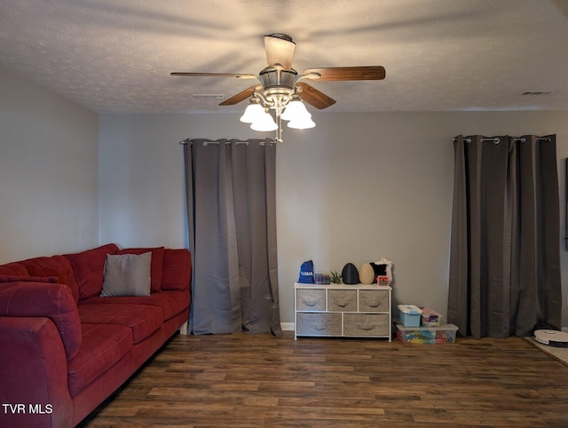 living room featuring a ceiling fan, visible vents, a textured ceiling, and wood finished floors