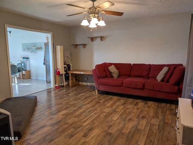 living room featuring baseboards, a textured ceiling, a ceiling fan, and wood finished floors