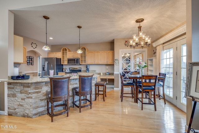 kitchen featuring light wood-style flooring, glass insert cabinets, appliances with stainless steel finishes, a textured ceiling, and light brown cabinetry