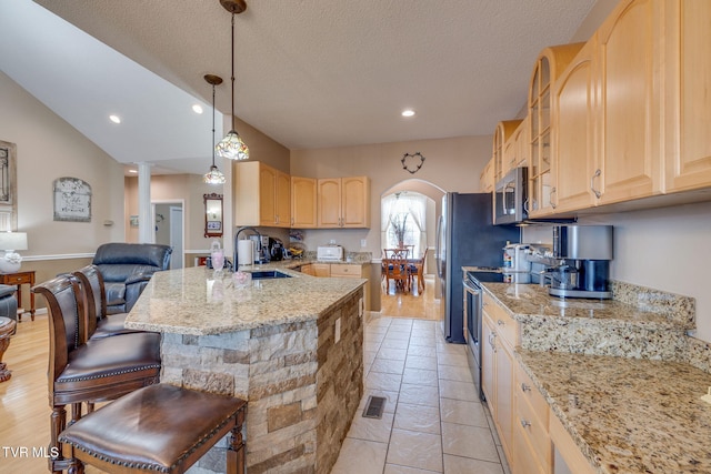 kitchen featuring stainless steel appliances, light brown cabinetry, a sink, a peninsula, and a kitchen breakfast bar