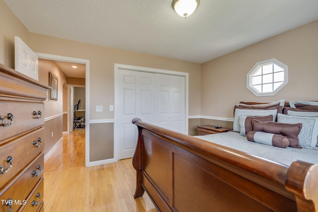 bedroom featuring a textured ceiling, light wood finished floors, a closet, and baseboards