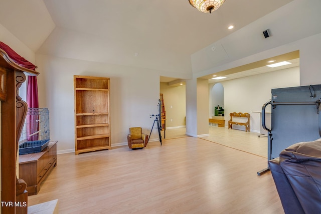 exercise room with arched walkways, recessed lighting, light wood-type flooring, and baseboards