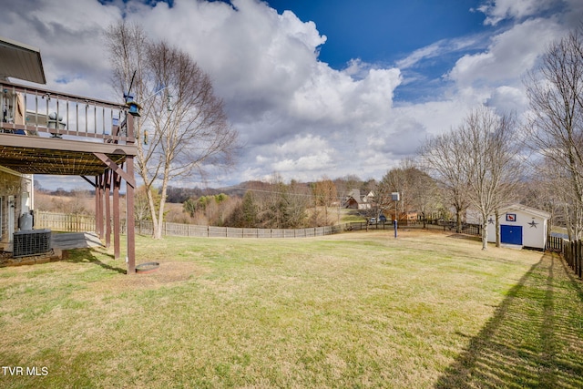 view of yard with central AC unit, fence, a deck, and an outbuilding