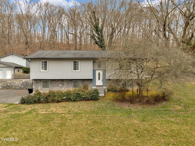 bi-level home featuring stone siding, a detached garage, and a front lawn