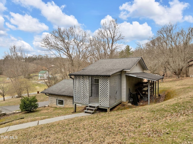 view of side of property with an outbuilding, a yard, and roof with shingles