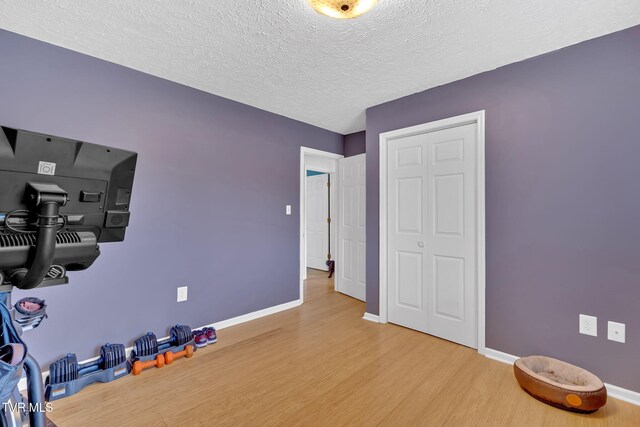 workout area with wood finished floors, baseboards, and a textured ceiling