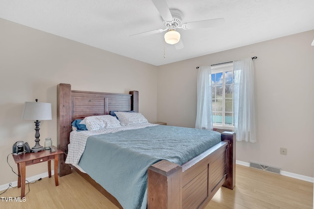 bedroom featuring light wood-type flooring, visible vents, baseboards, and ceiling fan