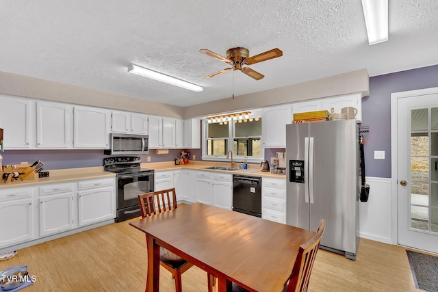 kitchen featuring black appliances, light countertops, light wood-style floors, white cabinetry, and a sink