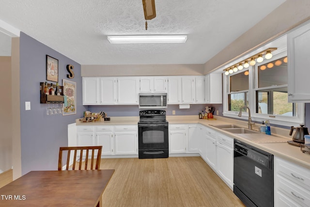 kitchen featuring a sink, black appliances, light countertops, white cabinetry, and light wood-type flooring