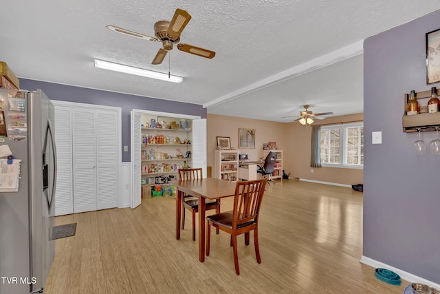 dining area featuring baseboards, a textured ceiling, light wood-type flooring, and ceiling fan