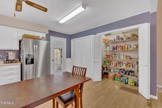 dining room with a ceiling fan, light wood-type flooring, and a textured ceiling