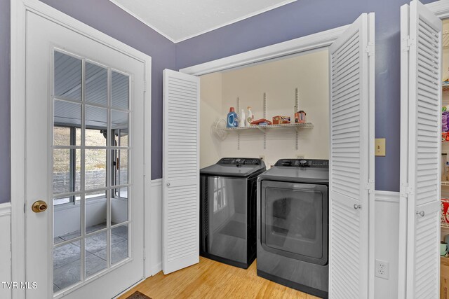 washroom featuring laundry area, light wood-style floors, wainscoting, and washer and clothes dryer