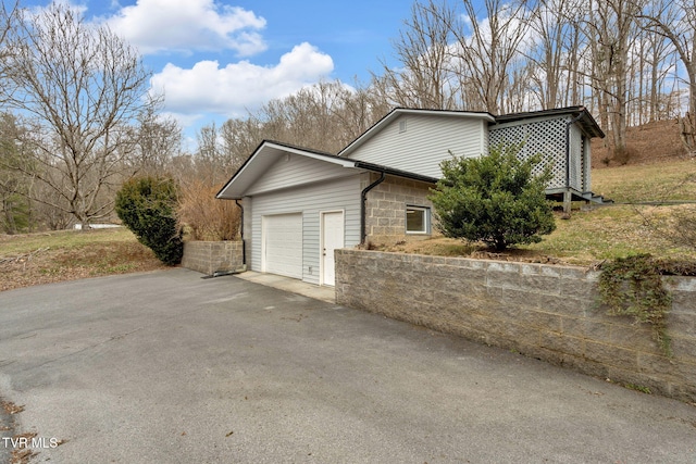 view of side of property featuring aphalt driveway and an attached garage