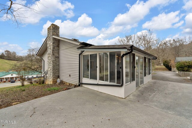 back of house featuring a patio area, a chimney, and a sunroom