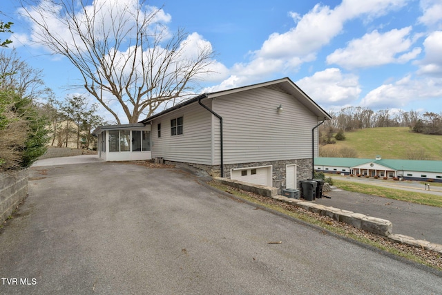 view of side of home with cooling unit, driveway, and a sunroom