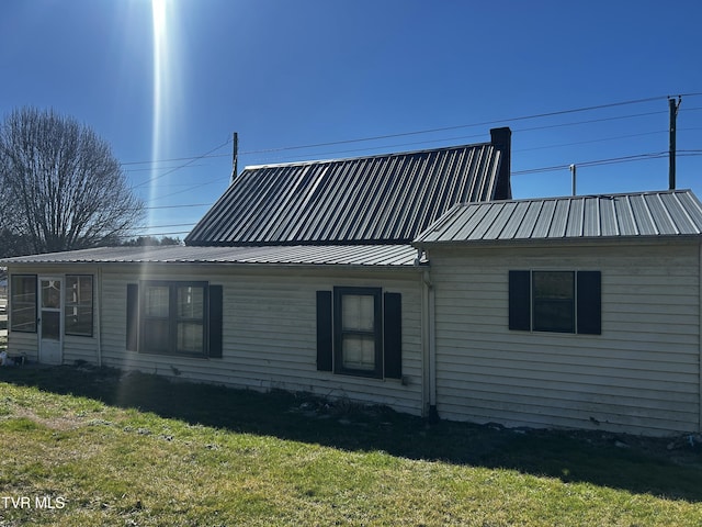 view of property exterior featuring metal roof and a yard