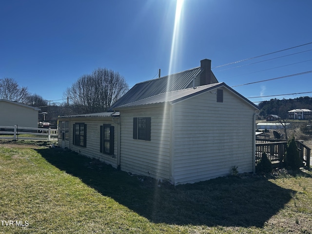 view of side of home with fence, metal roof, and a yard