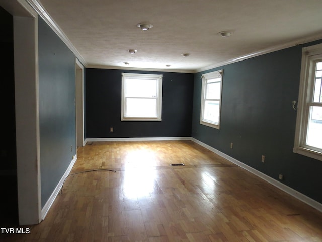 unfurnished room featuring baseboards, visible vents, ornamental molding, and wood finished floors