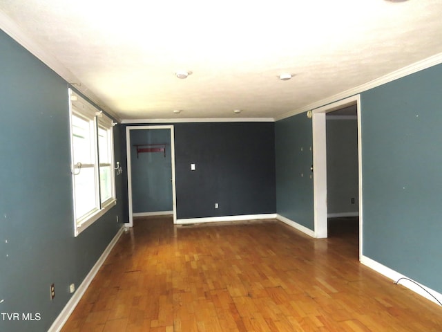 unfurnished room with ornamental molding, baseboards, and wood finished floors