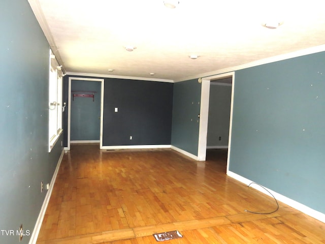 spare room with baseboards, hardwood / wood-style flooring, visible vents, and crown molding