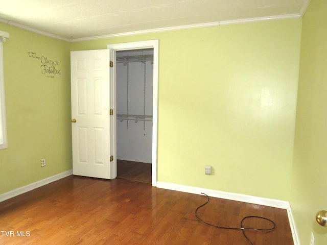 unfurnished room featuring crown molding, baseboards, and wood finished floors