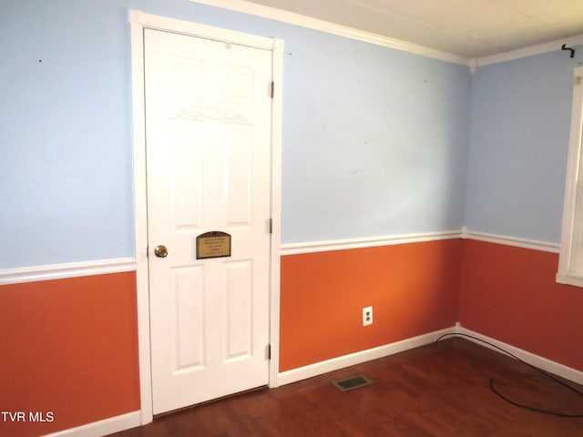 unfurnished room featuring crown molding, visible vents, baseboards, and wood finished floors