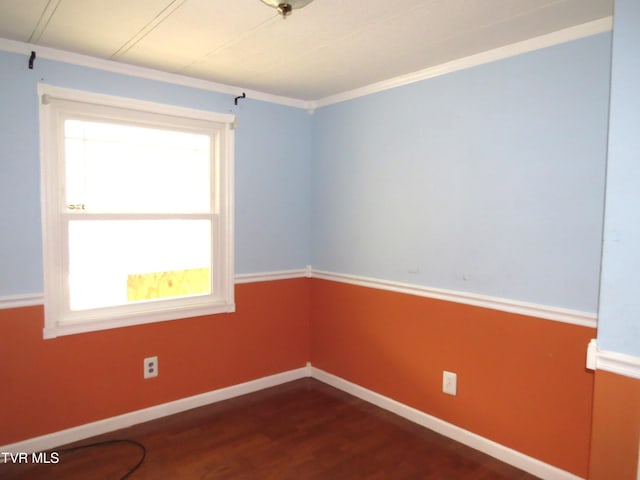 empty room featuring dark wood-style floors, baseboards, and crown molding