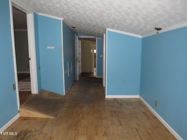 unfurnished room featuring a textured ceiling, ornamental molding, and wood finished floors