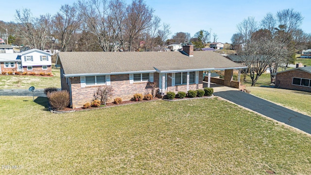 single story home with brick siding, driveway, a carport, a chimney, and a front yard