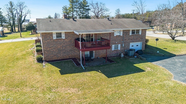 back of house featuring brick siding, a lawn, a chimney, and aphalt driveway