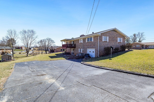 exterior space featuring driveway, an outbuilding, an attached garage, a yard, and brick siding