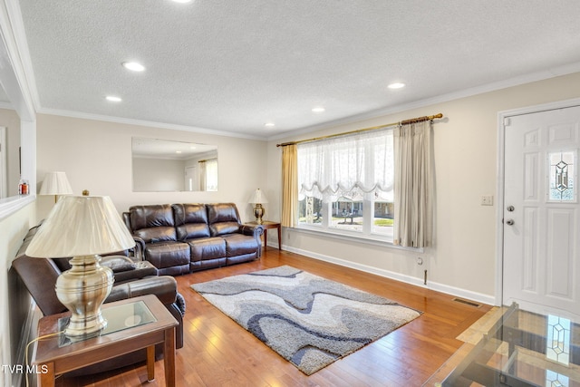 living room featuring wood-type flooring, a textured ceiling, visible vents, and crown molding