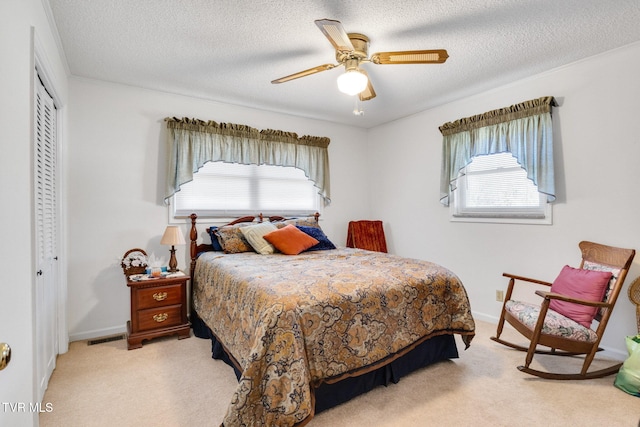 bedroom featuring visible vents, a ceiling fan, light colored carpet, a textured ceiling, and a closet