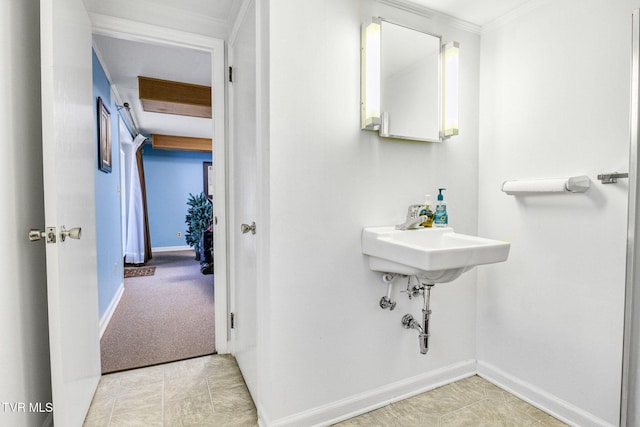 bathroom with crown molding, a sink, and baseboards