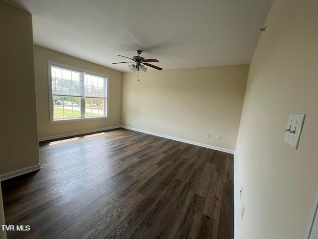 spare room with dark wood-style floors, ceiling fan, and baseboards