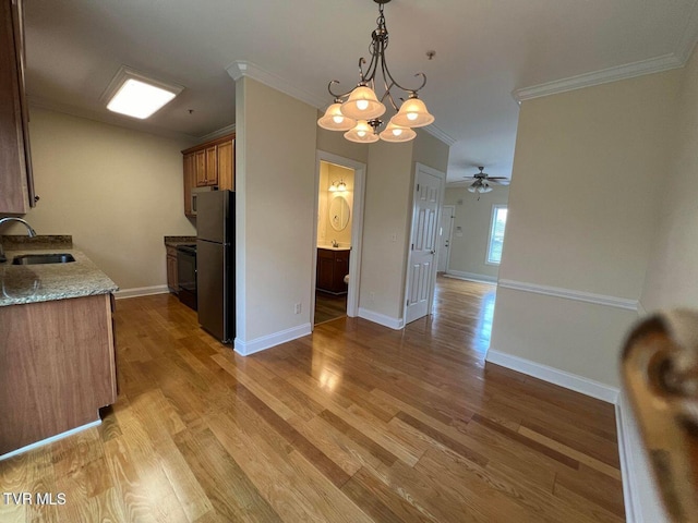 kitchen featuring light wood-style floors, ornamental molding, a sink, and freestanding refrigerator