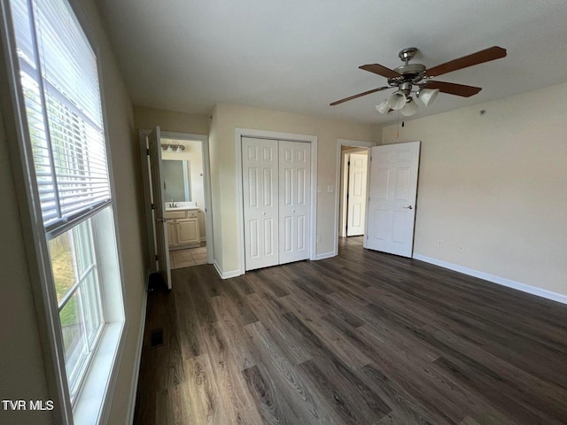 unfurnished bedroom featuring a closet, visible vents, dark wood-type flooring, connected bathroom, and baseboards