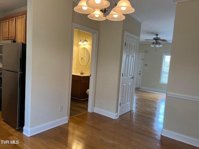 interior space with baseboards, wood finished floors, a sink, and crown molding